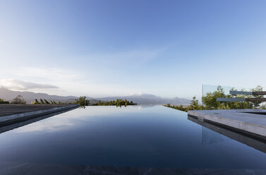 Ruhiger Luxus-Infinity-Pool mit Bergblick unter blauem Himmel - HOXF02373