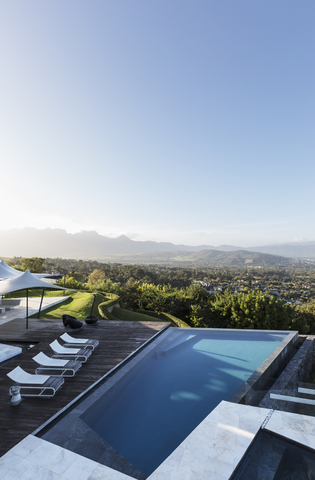 Home Schaufenster Außen Infinity-Pool und Terrasse mit Blick auf die Berge unter sonnigen blauen Himmel, lizenzfreies Stockfoto