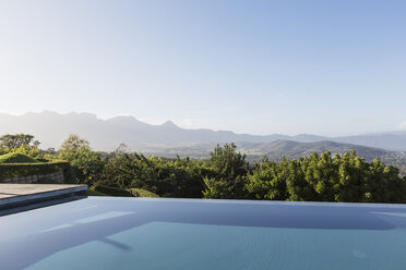 Ruhiger, luxuriöser Infinity-Pool mit Blick auf die Berge unter sonnigem, blauem Himmel - HOXF02389