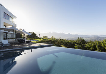 Ruhig, sonnig Haus Schaufenster Außenbereich mit Infinity-Pool und Blick auf die Berge unter blauem Himmel - HOXF02395