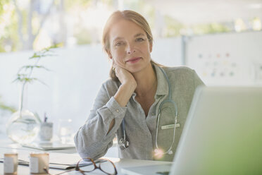 Porträt einer selbstbewussten Ärztin bei der Arbeit am Laptop in einer Arztpraxis - HOXF02425