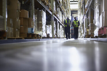 Workers walking in distribution warehouse aisle - HOXF02440