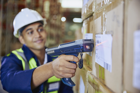 Worker with scanner scanning barcode on box in distribution warehouse stock photo