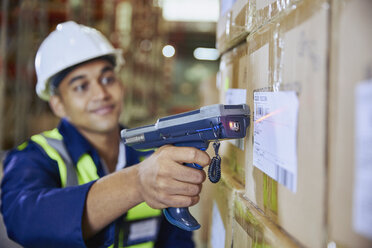 Arbeiter mit Scanner beim Scannen des Strichcodes auf einem Karton in einem Auslieferungslager - HOXF02446