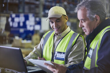 Arbeiter mit Klemmbrett und Laptop bei der Arbeit im Auslieferungslager - HOXF02466