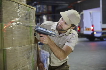 Staplerfahrer mit Scanner, der eine Palette mit Kisten im Auslieferungslager scannt - HOXF02472