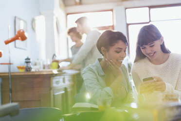 Young women texting with cell phone in apartment - HOXF02479