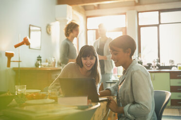 Young women roommates using laptop at table - HOXF02500