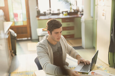 Junger Mann Student studiert am Laptop in der Küche - HOXF02515
