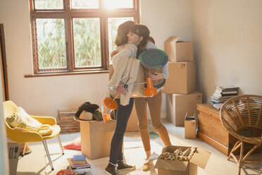 Mother and daughter hugging unpacking boxes in apartment - HOXF02542