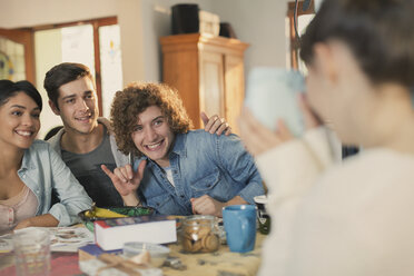 Young woman photographing friends with instant camera - HOXF02554