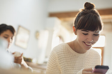 Smiling young woman texting with cell phone - HOXF02556