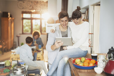 Smiling young couple using digital tablet in kitchen - HOXF02568