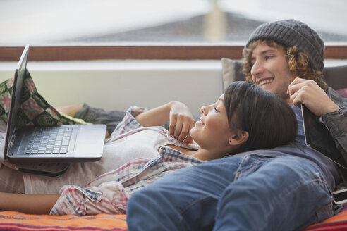 Junges Paar entspannt im Liegen mit Laptop - HOXF02590