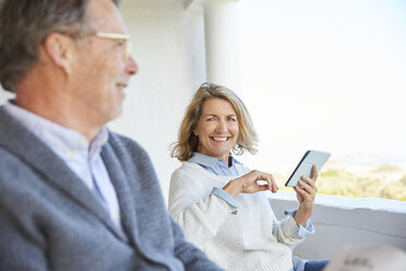 Senior couple using digital tablet on patio - HOXF02596