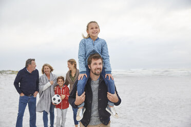 Multi-generation family walking on winter beach - HOXF02600