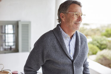 Smiling senior man looking away on patio - HOXF02607