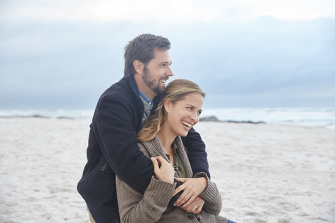 Glückliches Paar beim Umarmen am Winterstrand, lizenzfreies Stockfoto