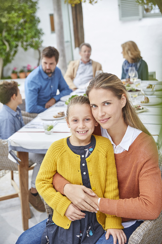 Portrait mother and daughter enjoying patio lunch with family stock photo