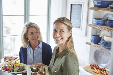 Portrait smiling mother and daughter serving food - HOXF02629