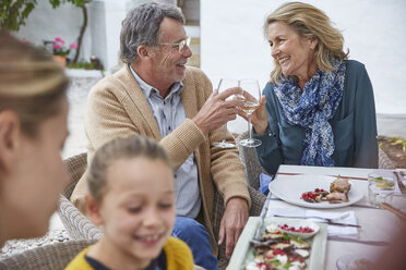 Glückliches älteres Paar stößt beim Mittagessen im Innenhof mit Weißweingläsern an - HOXF02631