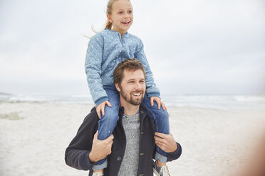 Father carrying daughter on shoulders on winter beach - HOXF02636