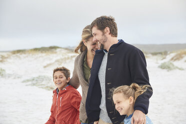 Happy family walking on winter beach - HOXF02638