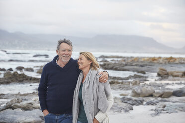 Smiling senior couple walking on winter beach - HOXF02641