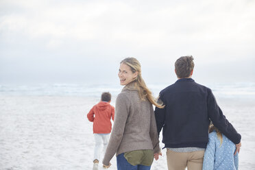 Porträt einer glücklichen Familie, die am Winterstrand spazieren geht - HOXF02643