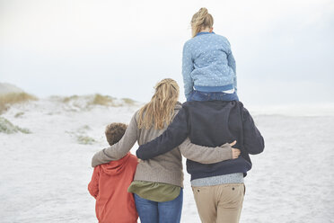 Affectionate family walking on winter beach - HOXF02652