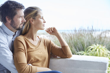 Serene couple looking away on patio - HOXF02654