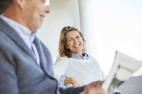 Lächelndes älteres Ehepaar liest Zeitung auf der Terrasse - HOXF02657