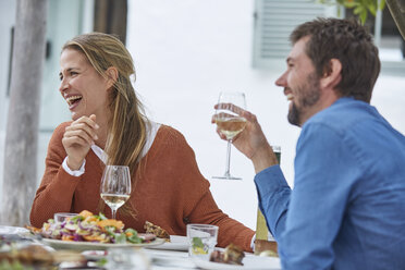 Lachendes Paar trinkt Weißwein und isst zu Mittag am Terrassentisch - HOXF02667