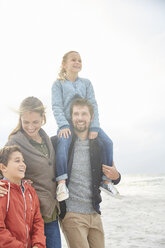 Lächelnde Familie beim Spaziergang am Winterstrand - HOXF02672