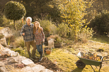 Portrait lächelndes Paar bei der Gartenarbeit im sonnigen Herbstgarten - HOXF02686
