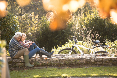 Zärtliches Paar umarmt auf Steinmauer im Herbst Park, lizenzfreies Stockfoto