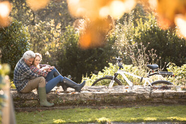 Zärtliches Paar umarmt auf Steinmauer im Herbst Park - HOXF02693