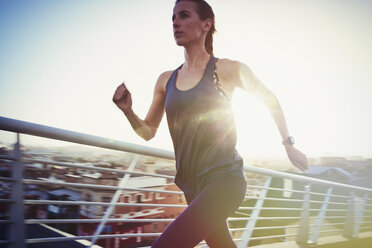 Determined female runner running on urban footbridge - HOXF02714