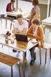 Geschäftsleute trinken Kaffee und arbeiten am Laptop in einem Cafe - HOXF02732