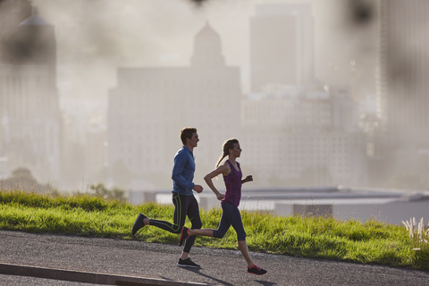 Läuferpaar auf sonnigem städtischem Bürgersteig, lizenzfreies Stockfoto