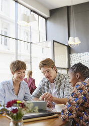 Geschäftsleute treffen sich in einem Café und benutzen ein digitales Tablet - HOXF02744