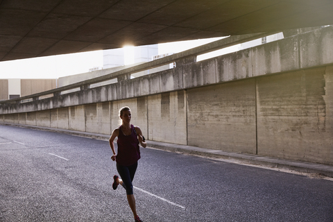 Läuferin läuft in einen städtischen Tunnel, lizenzfreies Stockfoto
