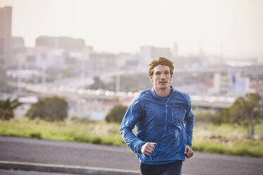 Male runner running on urban city street - HOXF02756