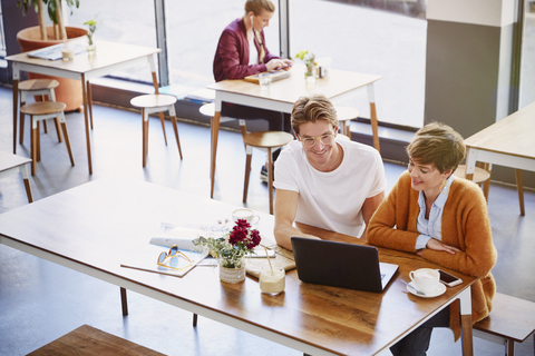 Geschäftsleute, die Kaffee trinken und einen Laptop in einem Café benutzen, lizenzfreies Stockfoto