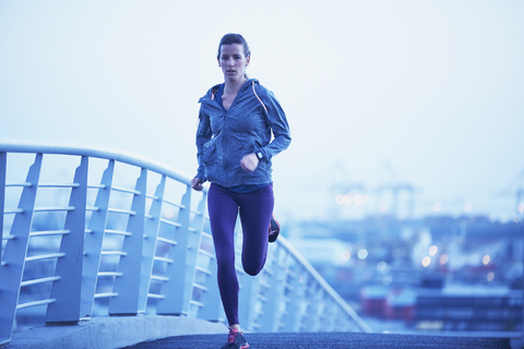 Läuferin auf städtischer Fußgängerbrücke in der Morgendämmerung, lizenzfreies Stockfoto