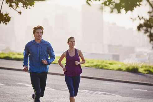 Läuferpaar läuft auf einer sonnigen städtischen Straße - HOXF02788