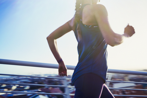 Läuferin läuft auf sonniger Fußgängerbrücke, lizenzfreies Stockfoto