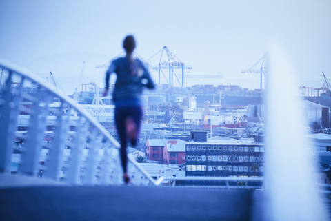 Läuferin auf städtischer Fußgängerbrücke in der Morgendämmerung, lizenzfreies Stockfoto