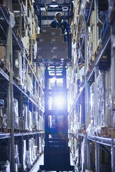 Worker operating forklift stacking cardboard boxes on distribution warehouse shelves - HOXF02839