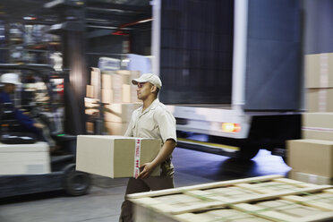 Arbeiter trägt Karton an der Laderampe eines Vertriebslagers - HOXF02841